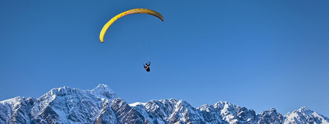 Paraglider over snow capped mountains